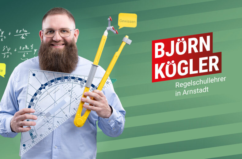 Björn Kögler vor einem grün-gestreiften Hintergrund. In der Hand hält er ein Geodreieck und einen Zirkel. Beides ist für eine Tafel und dementsprechend groß.